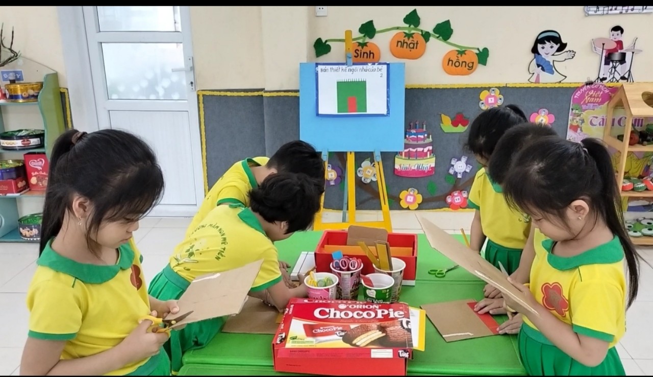 Hình ảnh trẻ đo, cắt bìa cát tông thành các bức tường